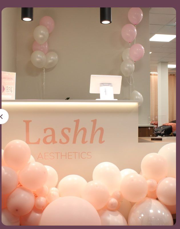 Lashh Aesthetics reception desk decorated with blush and cream balloons